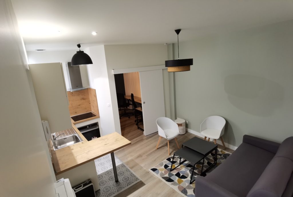 Vue d'ensemble de la pièce de vie avec cuisine ouverte et salon dans le studio à Amidonniers