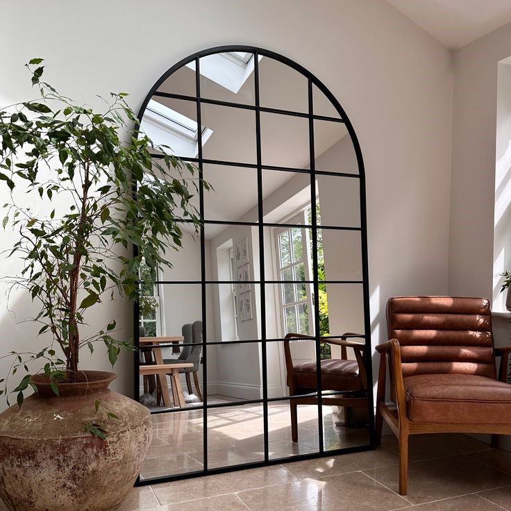 Grand miroir arche en acier noir dans une entrée contemporaine