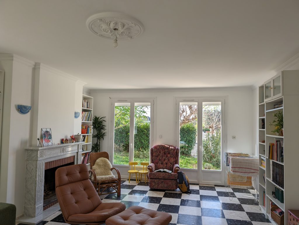 Grand salon avec des fauteils et deux grandes portes vitrées de la maison L à Toulouse