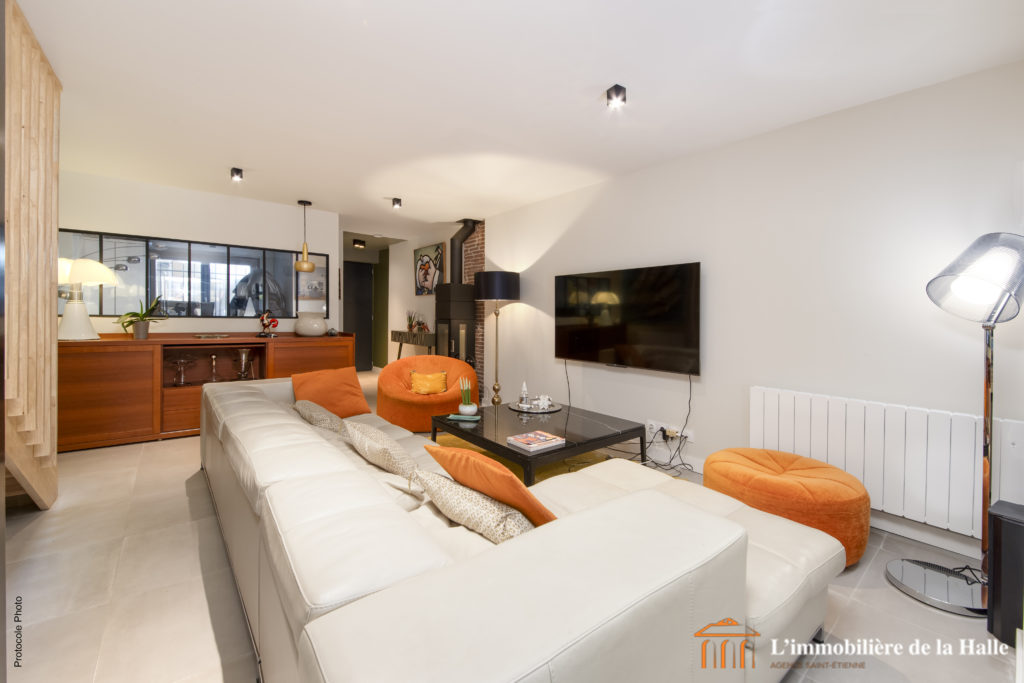 Grand salon avec un canapé, une télévision et des coussins orange pour la maison R à Toulouse